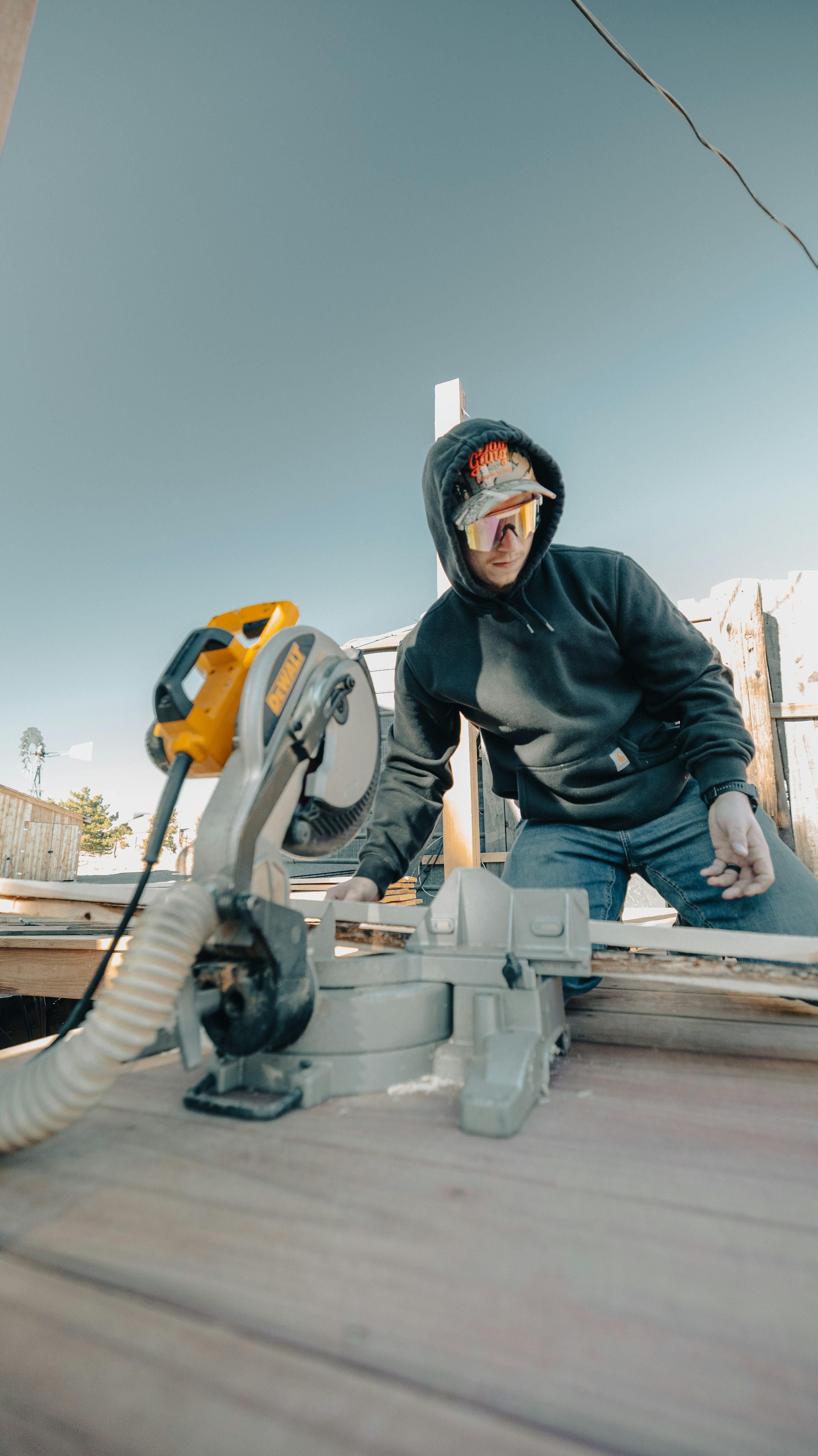 A Troy Wayne Contractors crew member cutting lumber on a job site.