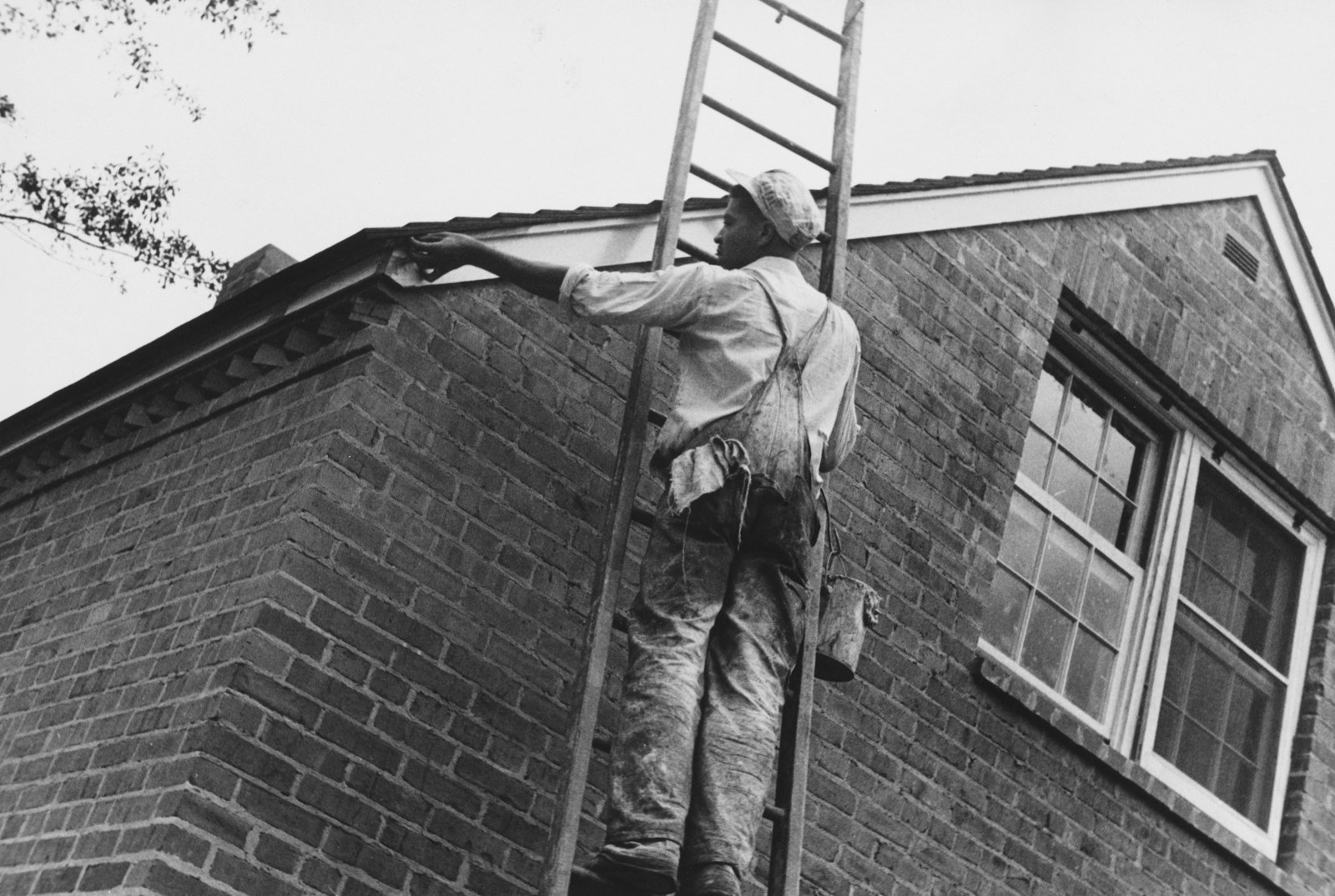 Painter working on the exterior of a brick house.